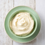 Top view of creamy vanilla keto frosting in a green bowl on matching plate