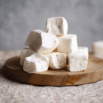 Plain white sugar free marshmallows stacked on wooden board