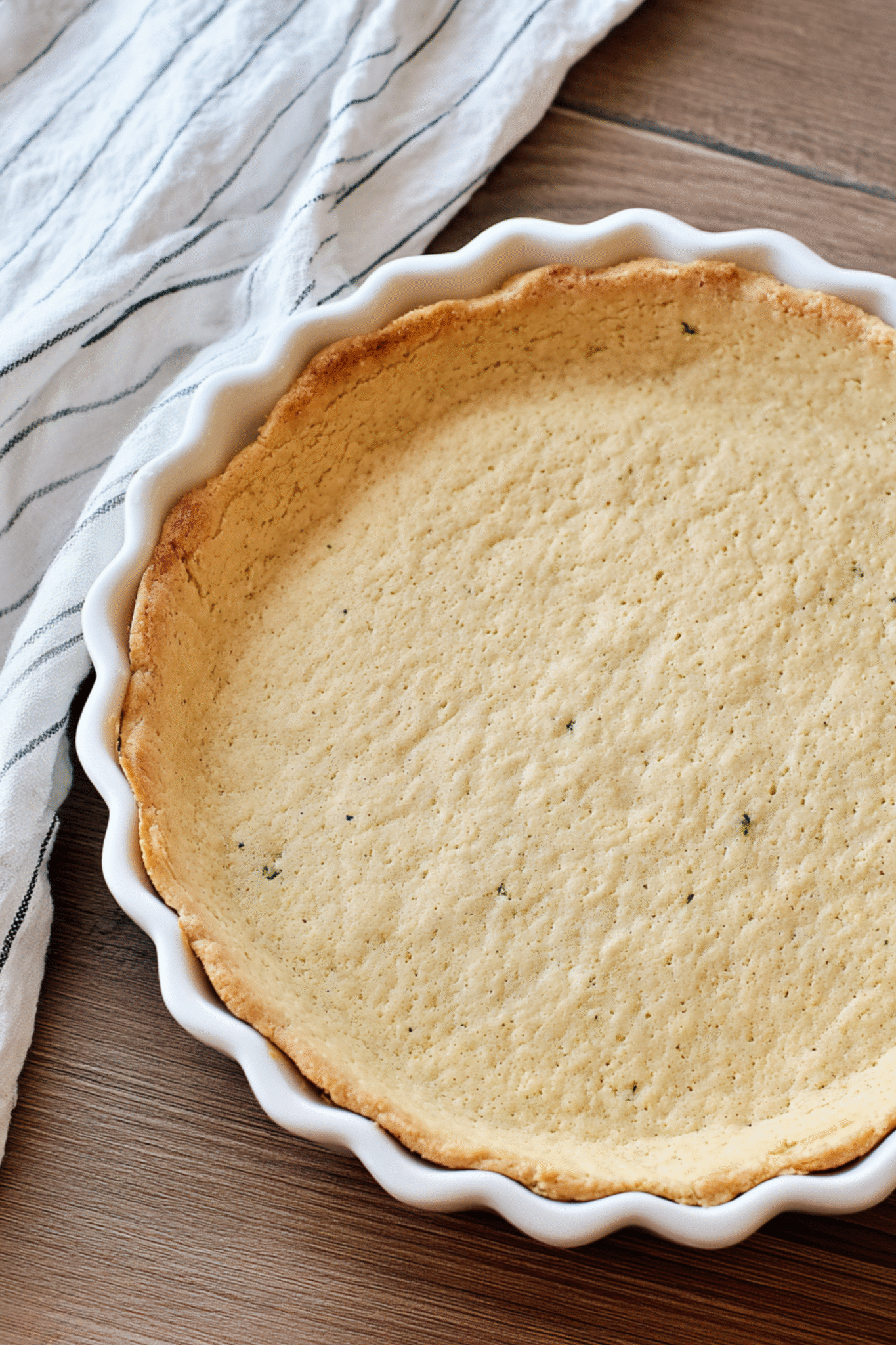 Almond Flour Quiche Crust Baked to Golden Perfection Fully baked almond flour quiche crust in white ceramic dish