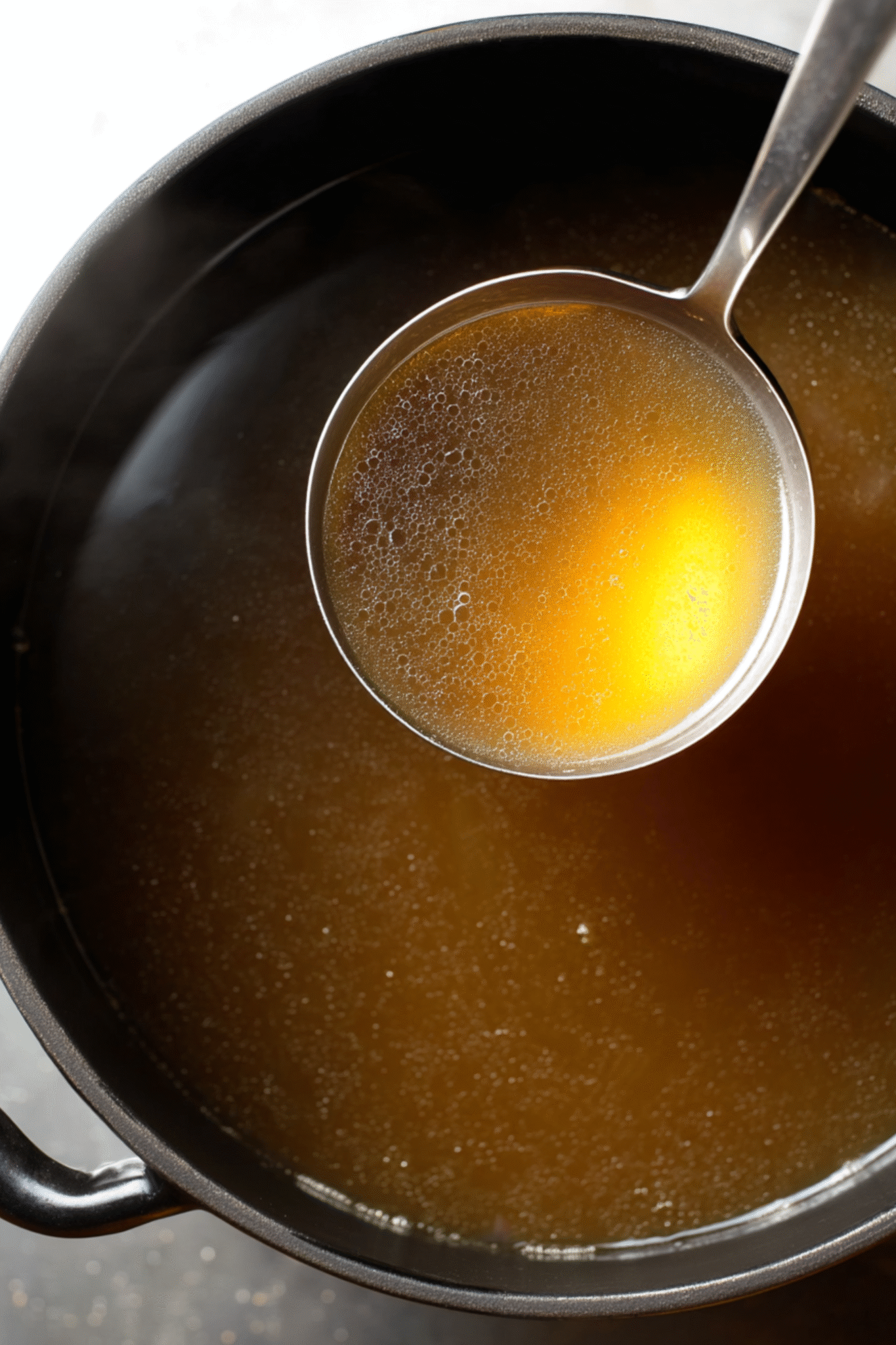 Homemade Beef Bone Broth Simmering in Pot Homemade Beef Bone Broth in a pot with ladle