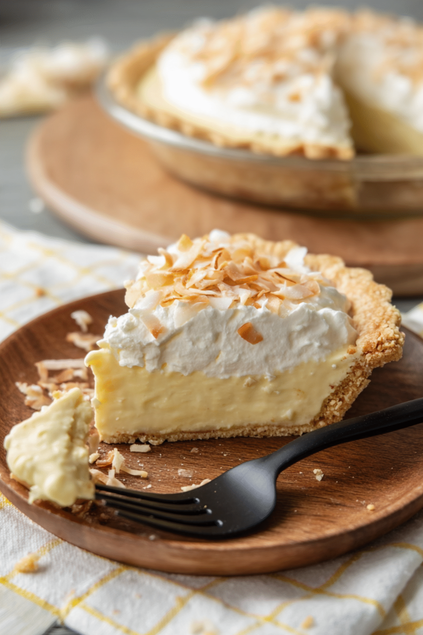 Slice of Coconut Cream Pie in Easy Keto Pie Crust Serving of coconut cream pie in easy keto pie crust on a wooden plate with fork